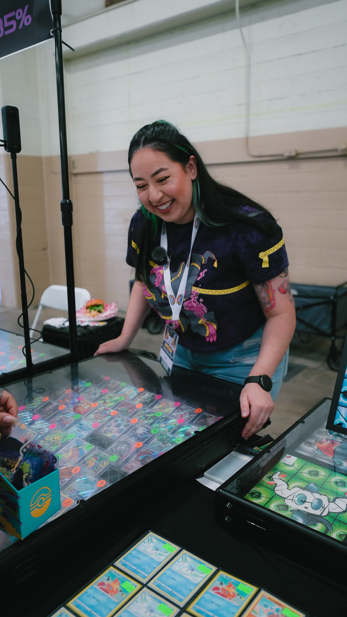 Vendor smiling while showing a display case of Pokémon cards to a customer