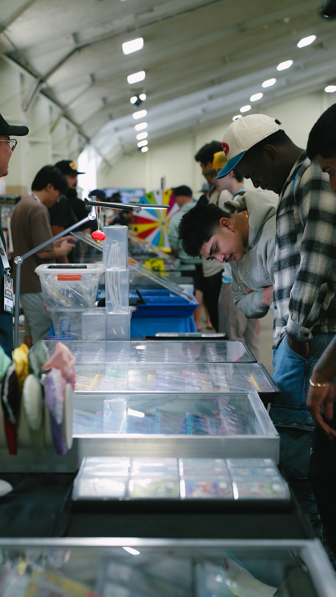 Group of attendees browsing display cases of trading cards under a work lamp