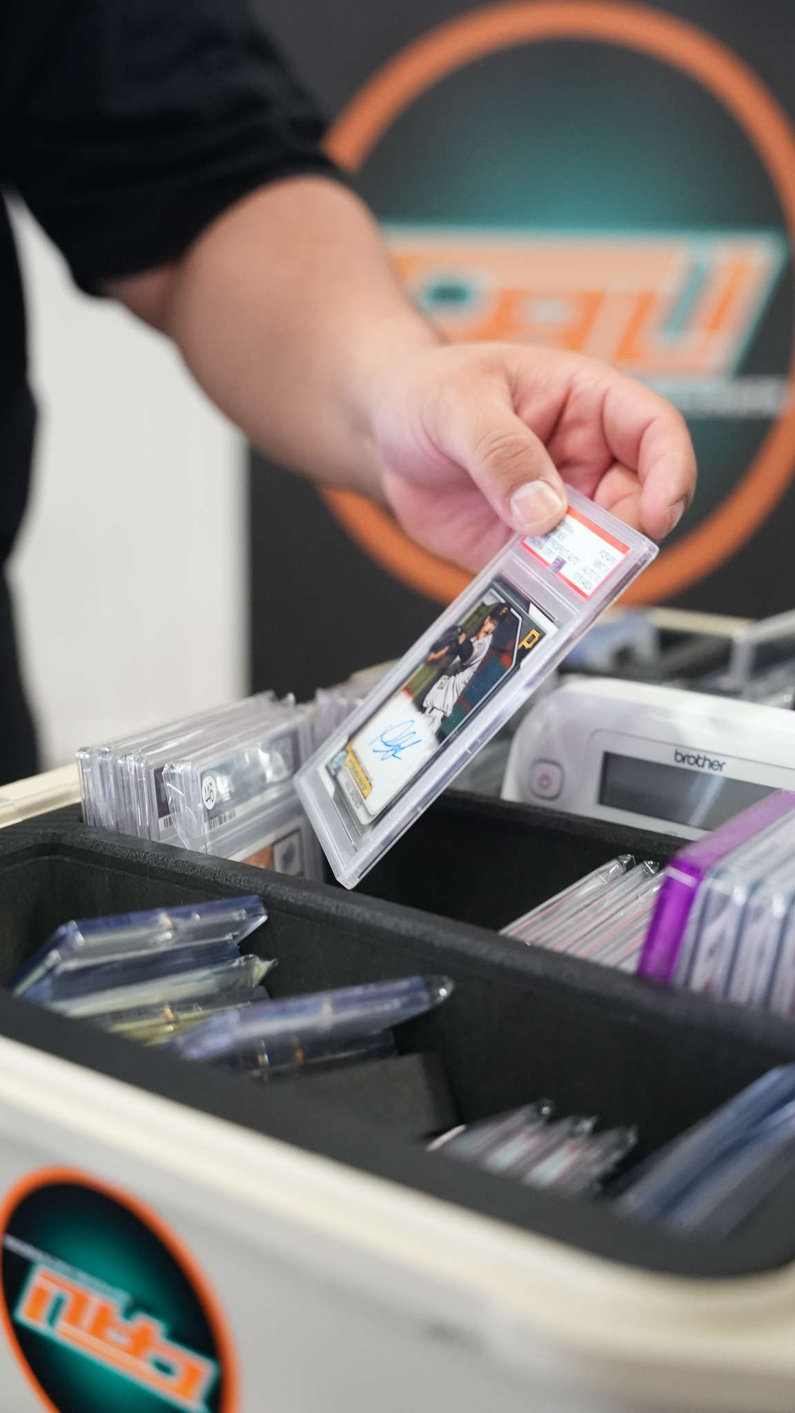 Close-up of a hand holding a graded, autographed baseball card in a PSA case